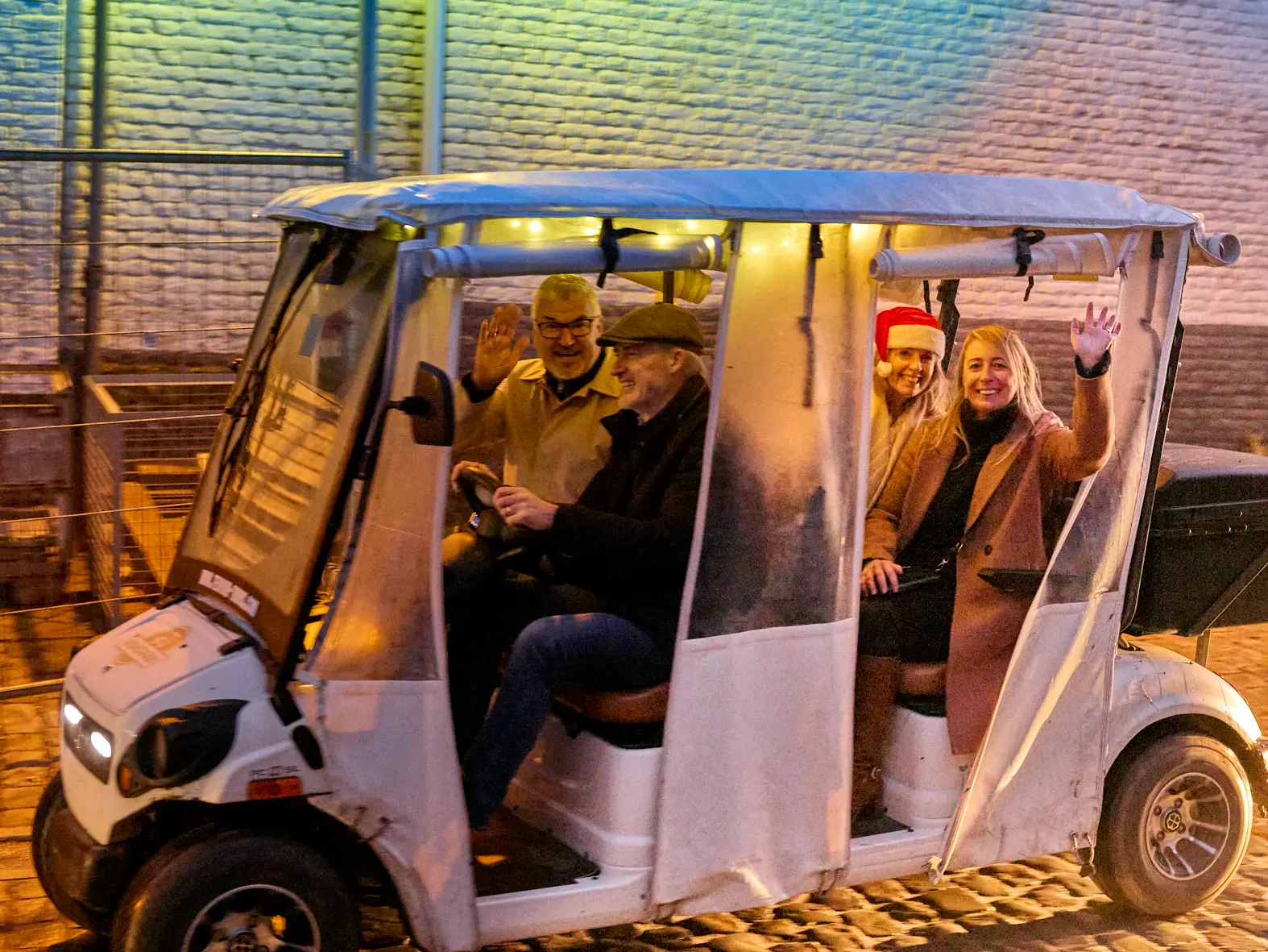 Gasten in een feestelijk verlicht Wijnsafari-wagentje tijdens The Christmas Ride