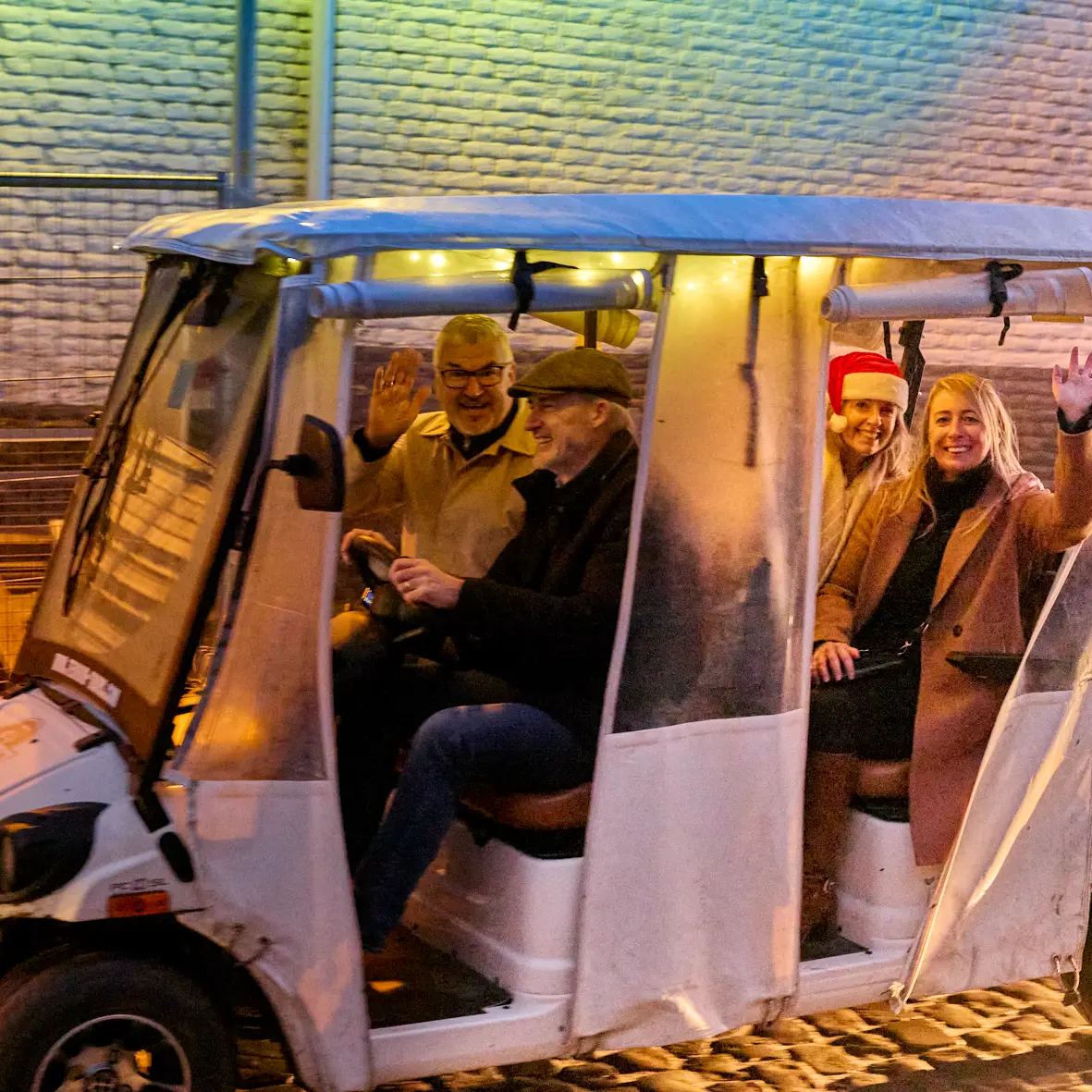 Gasten in een feestelijk verlicht Wijnsafari-wagentje tijdens The Christmas Ride